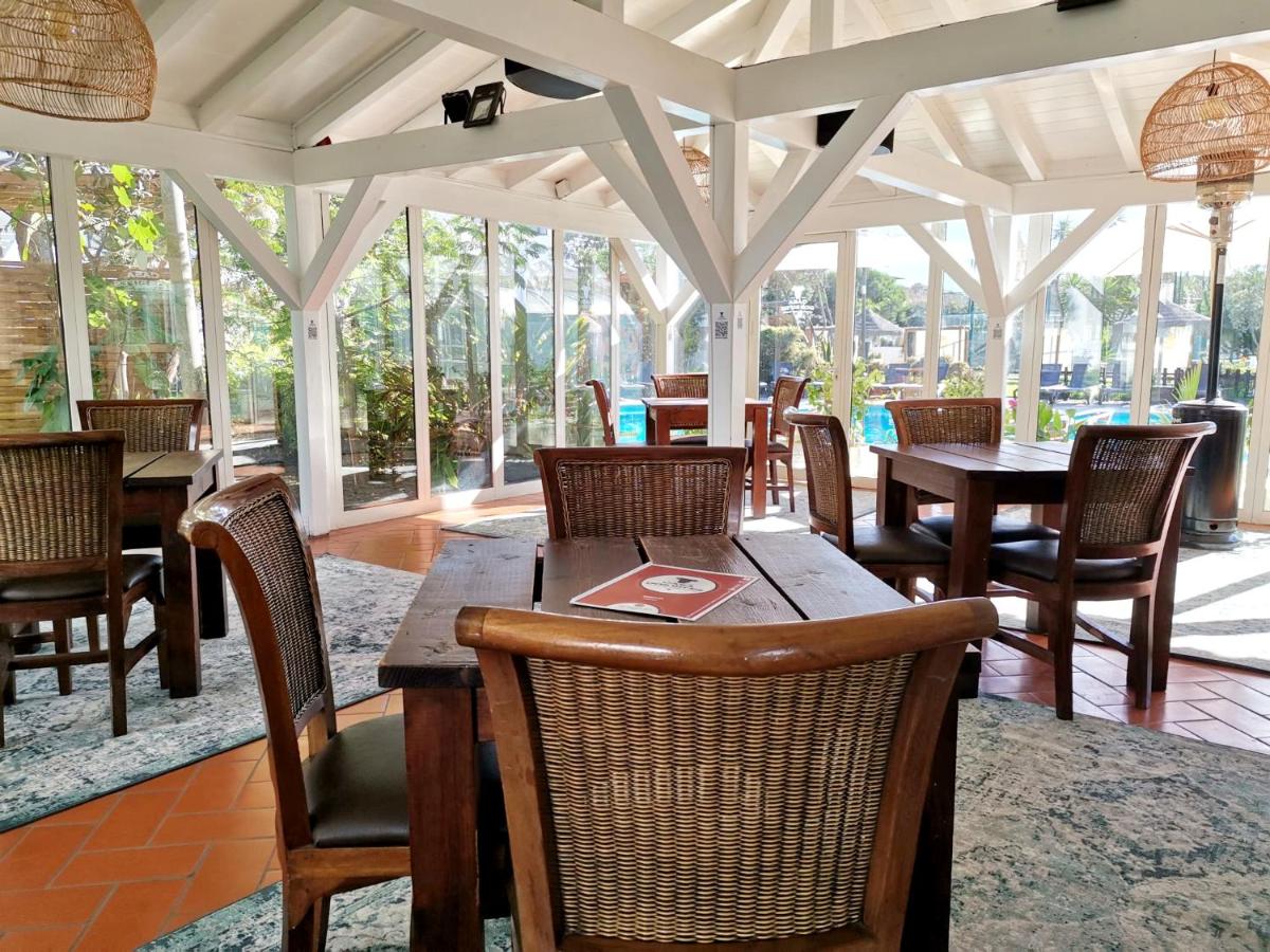 uma sala de jantar com mesas, cadeiras e janelas em Duna Parque Beach Club - Duna Parque Group em Vila Nova de Milfontes