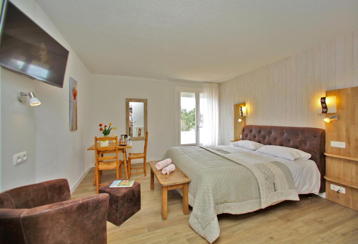 une chambre avec un lit, une table et des chaises dans l'établissement Logis Hotel Le Tropicana, à Douville