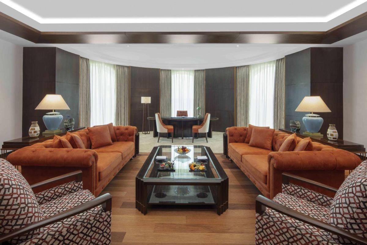 a living room with brown leather couches and a table at Radisson Blu Plaza Hotel Mysore in Mysore