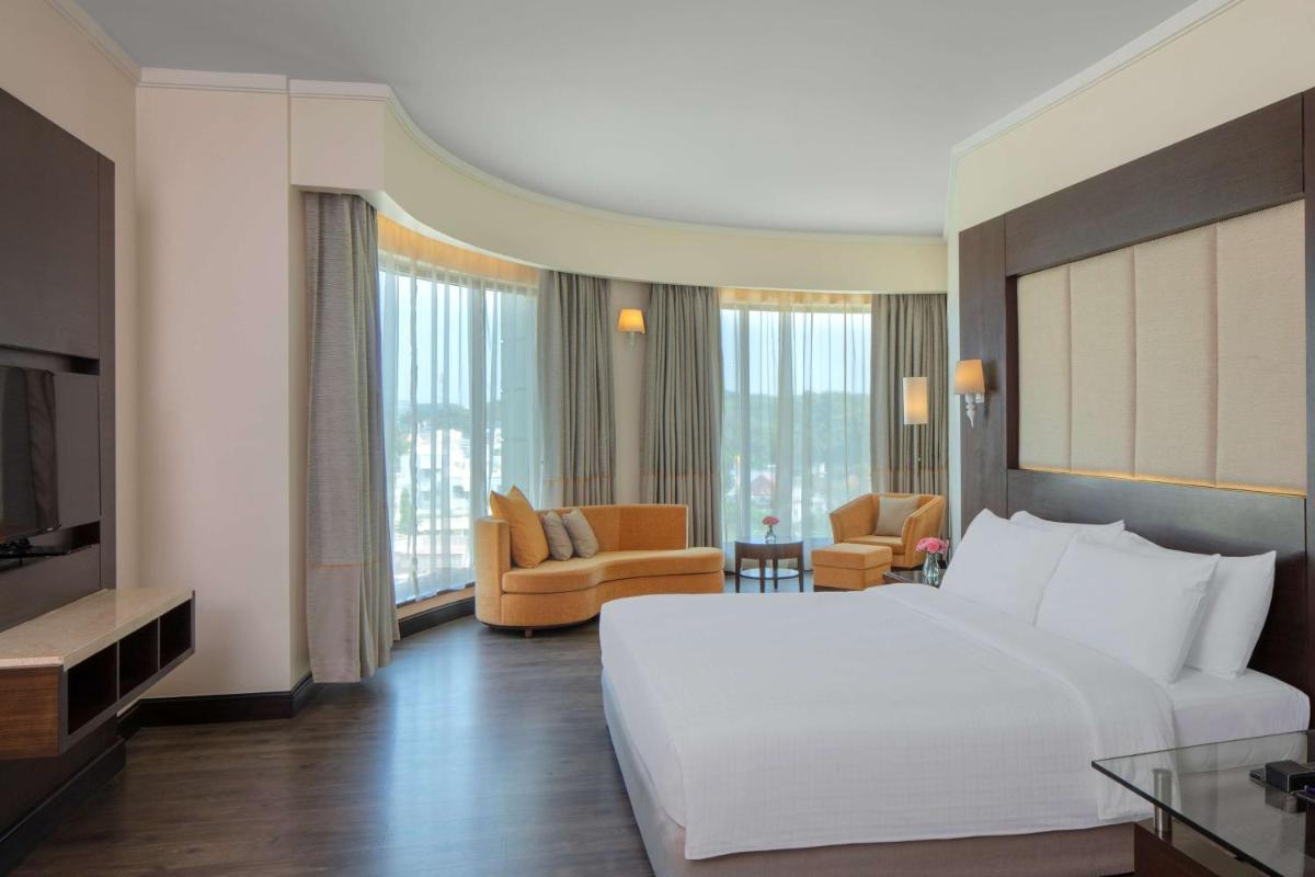 a hotel room with a large white bed and furniture at Radisson Blu Plaza Hotel Mysore in Mysore