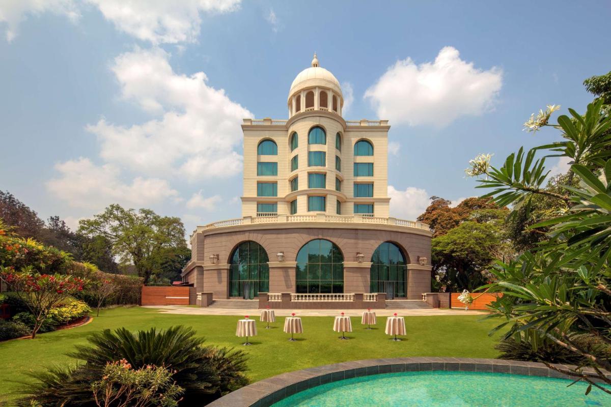 a building with a pool in front of it at Radisson Blu Plaza Hotel Mysore in Mysore