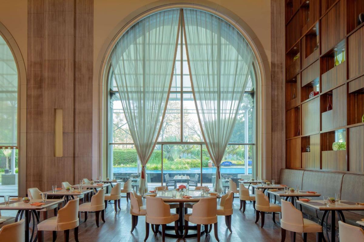 a dining room with tables and chairs and a large window at Radisson Blu Plaza Hotel Mysore in Mysore