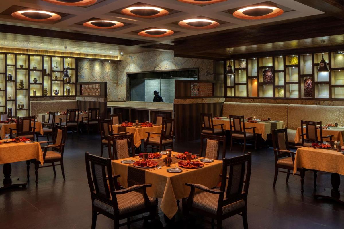 a restaurant with tables and chairs in a room at Radisson Blu Plaza Hotel Mysore in Mysore