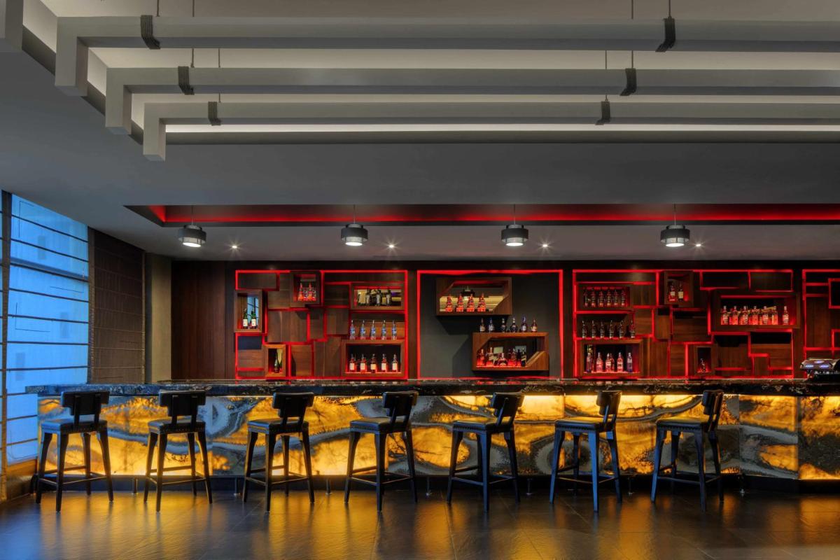 a bar in a restaurant with red cabinets and stools at Radisson Blu Plaza Hotel Mysore in Mysore