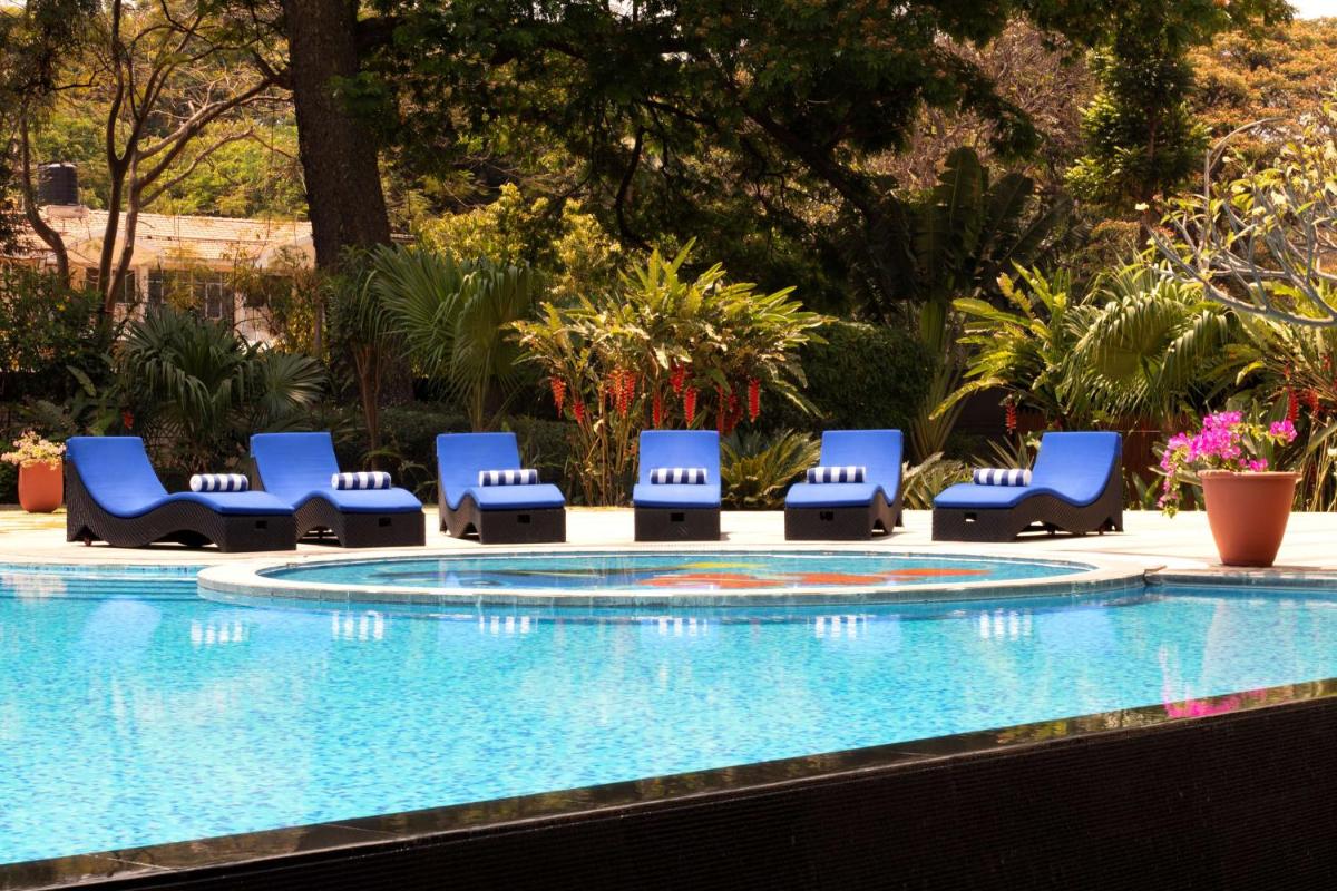 a group of blue lounge chairs next to a swimming pool at Radisson Blu Plaza Hotel Mysore in Mysore