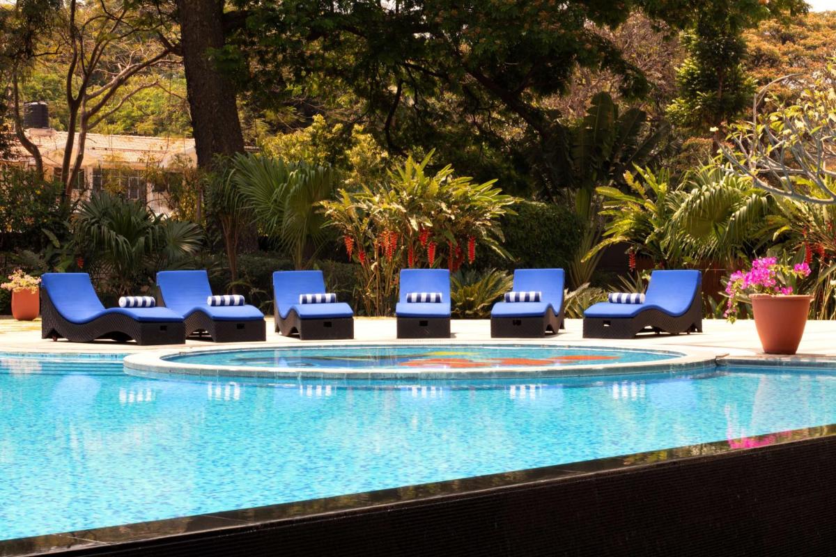 a group of blue lounge chairs next to a swimming pool at Radisson Blu Plaza Hotel Mysore in Mysore