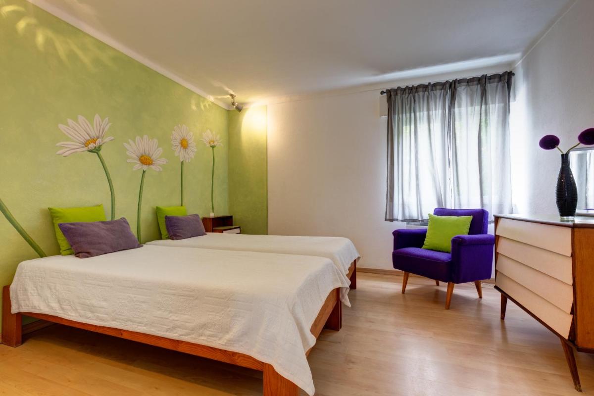 um quarto com uma cama, uma cadeira e flores na parede em Duna Parque Beach Club - Duna Parque Group em Vila Nova de Milfontes