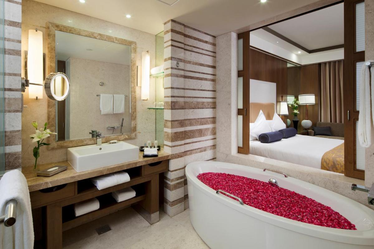 a bathroom with a large tub and a bedroom at Crowne Plaza New Delhi Okhla by IHG in New Delhi