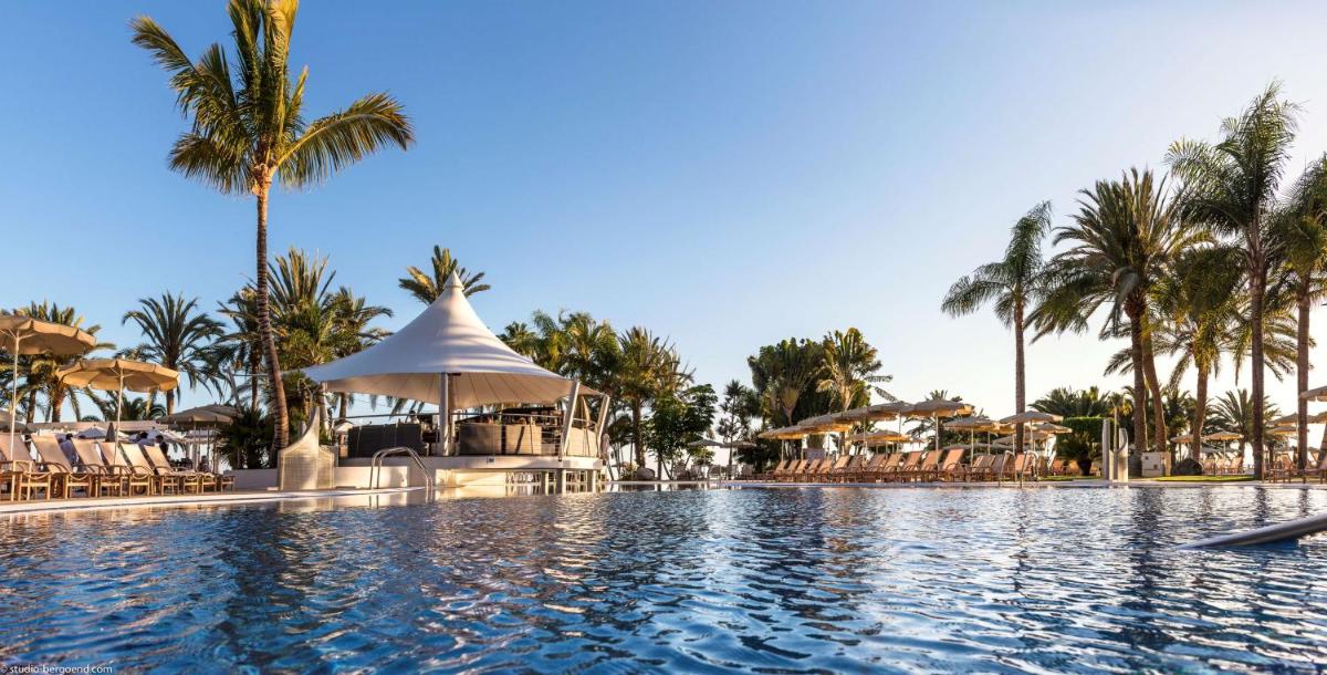 una piscina en un resort con palmeras en Radisson Blu Resort Gran Canaria, en La Playa de Arguineguín