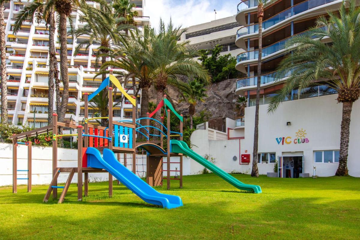un parque infantil frente a un edificio con palmeras en Radisson Blu Resort Gran Canaria, en La Playa de Arguineguín