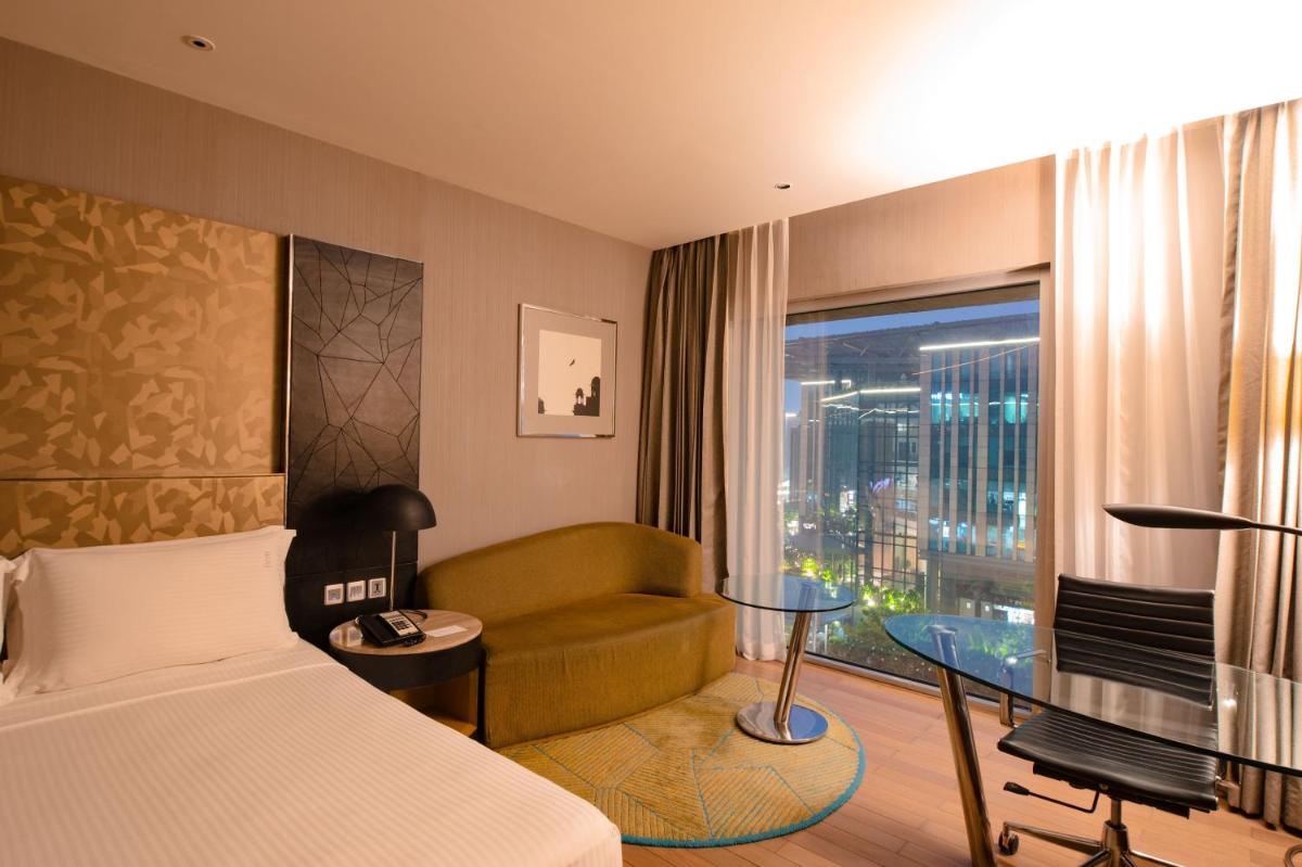 a hotel room with a bed and a couch and a window at Holiday Inn New Delhi Aerocity by IHG in New Delhi