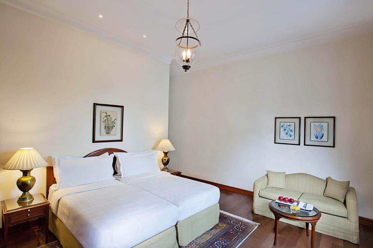 a bedroom with a large white bed and a couch at Maidens Hotel New Delhi in New Delhi