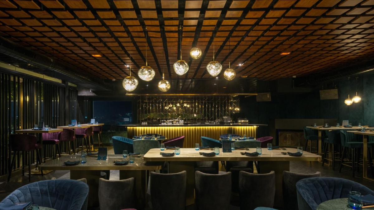 a dining room with tables and chairs and a chandelier at Novotel Chennai Chamiers Road in Chennai