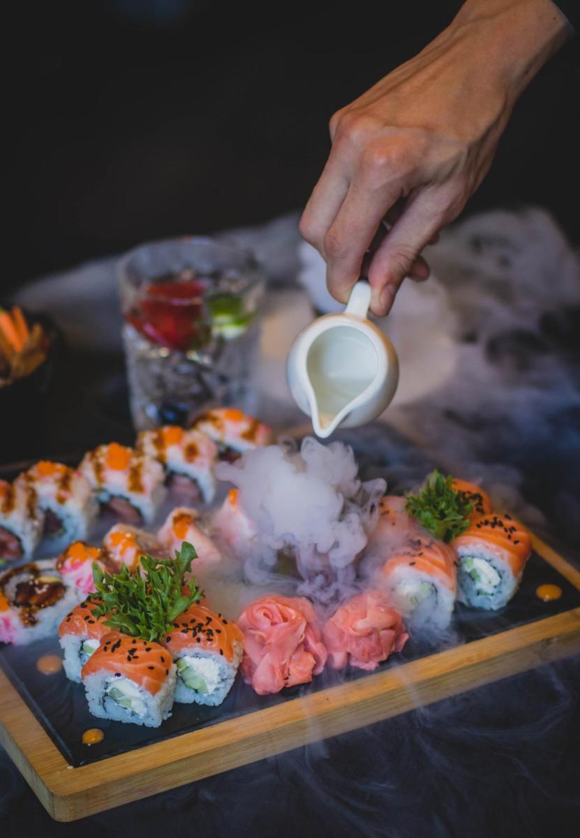 a person holding a cup of milk over sushi at Novotel Chennai Chamiers Road in Chennai