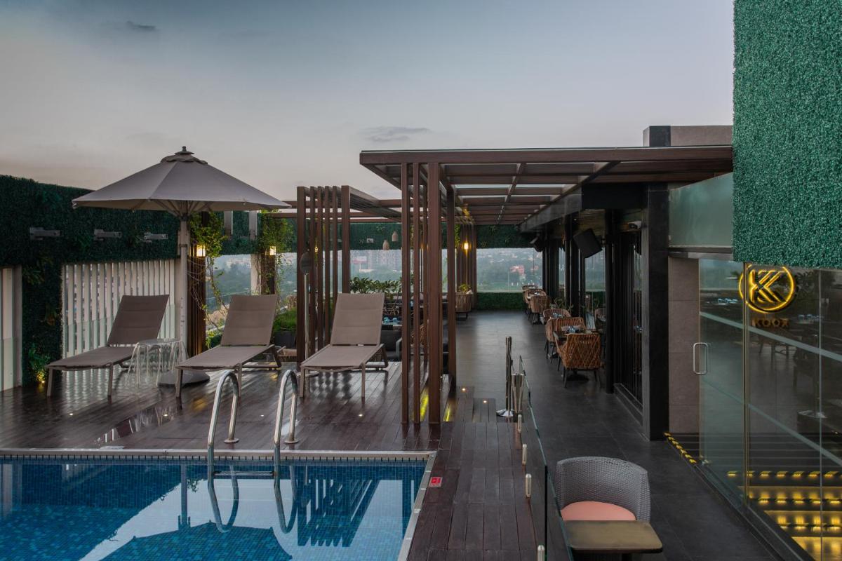 a balcony with a pool and chairs and an umbrella at Novotel Chennai Chamiers Road in Chennai