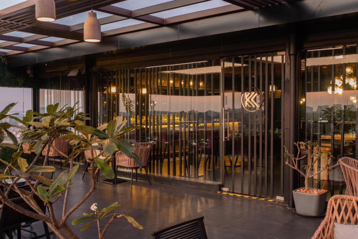 a restaurant with glass doors and chairs and tables at Novotel Chennai Chamiers Road in Chennai