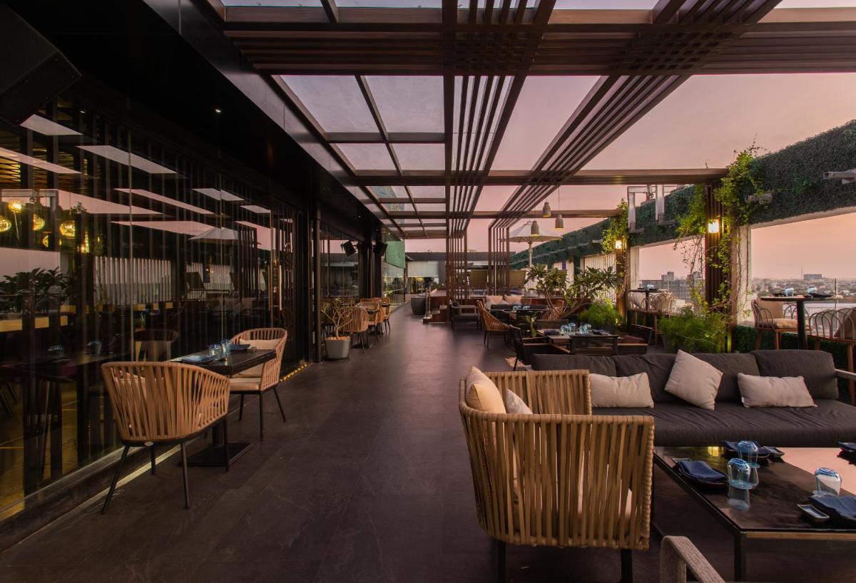 a restaurant with couches and tables and chairs at Novotel Chennai Chamiers Road in Chennai