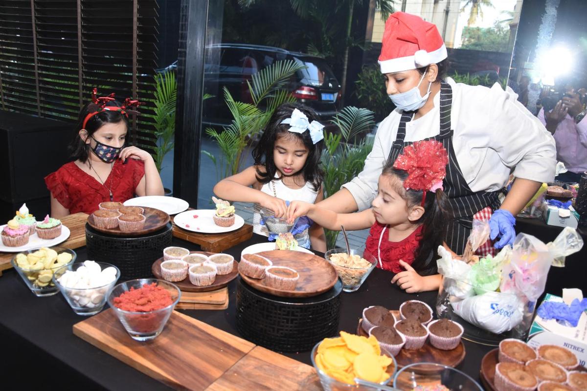 a group of children standing around a table with cupcakes at Novotel Chennai Chamiers Road in Chennai
