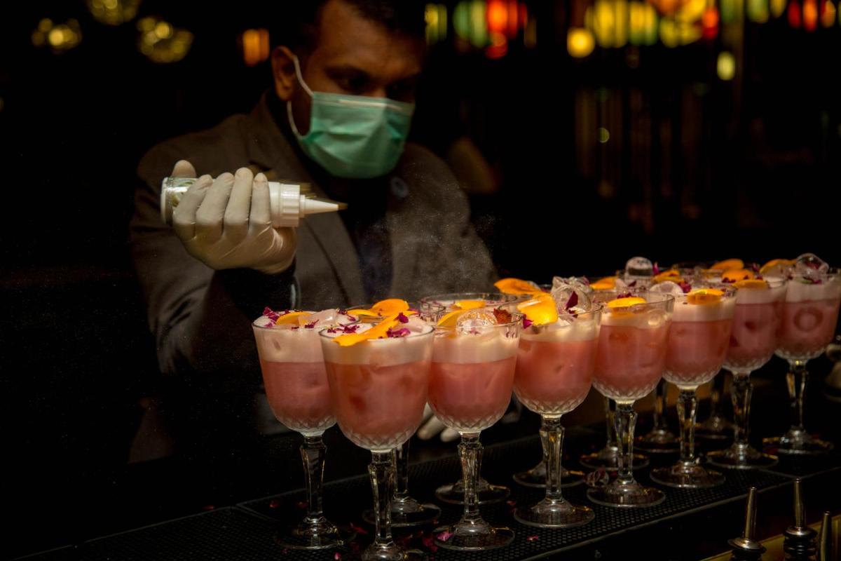 a man in a mask standing next to a row of glasses at Novotel Chennai Chamiers Road in Chennai