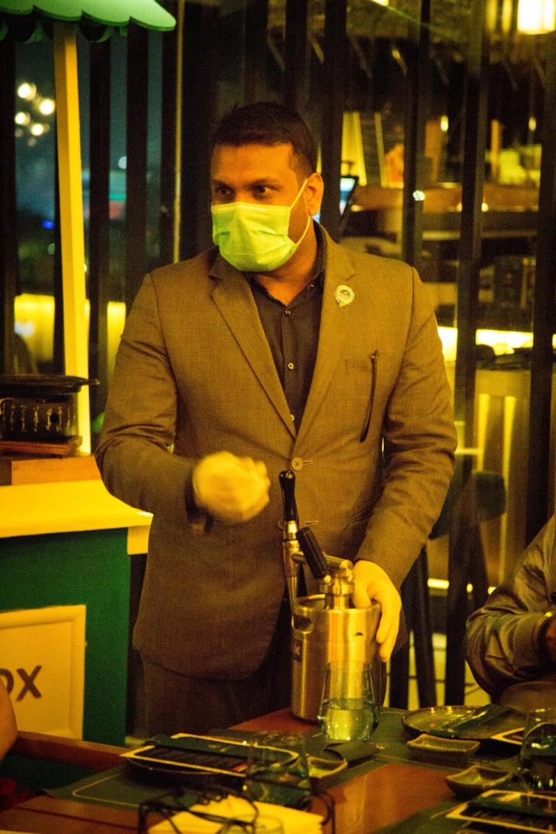 a man wearing a mask and gloves standing next to a blender at Novotel Chennai Chamiers Road in Chennai