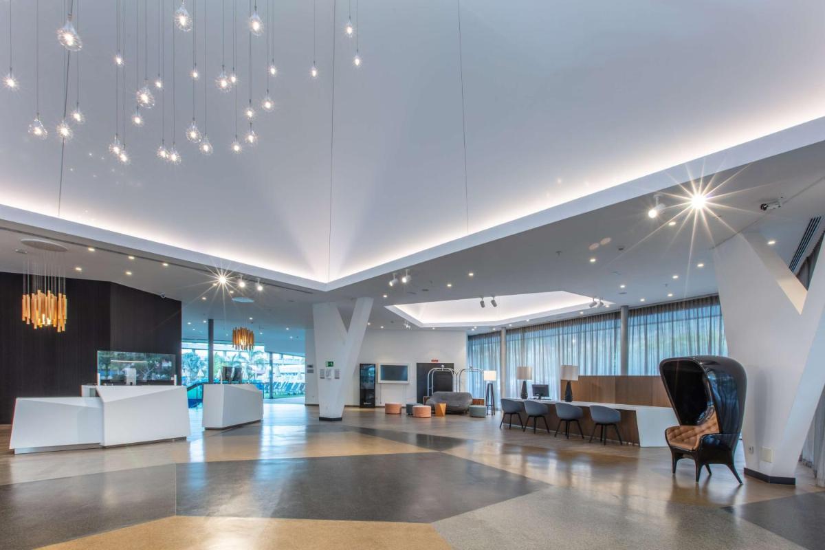 Un vestíbulo de oficina con un mostrador de recepción y sillas. en Radisson Blu Resort & Spa, Gran Canaria Mogan, en Puerto de Mogán