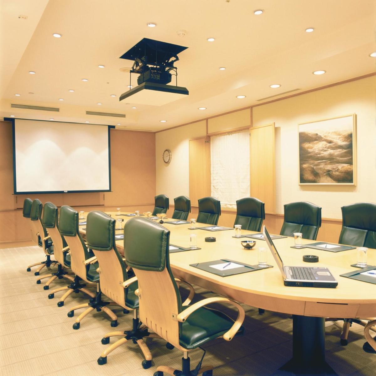 a conference room with a large table with chairs and a laptop at Trident Nariman Point in Mumbai a conference room with a large table with chairs and a laptop at Trident Nariman Point in Mumbai