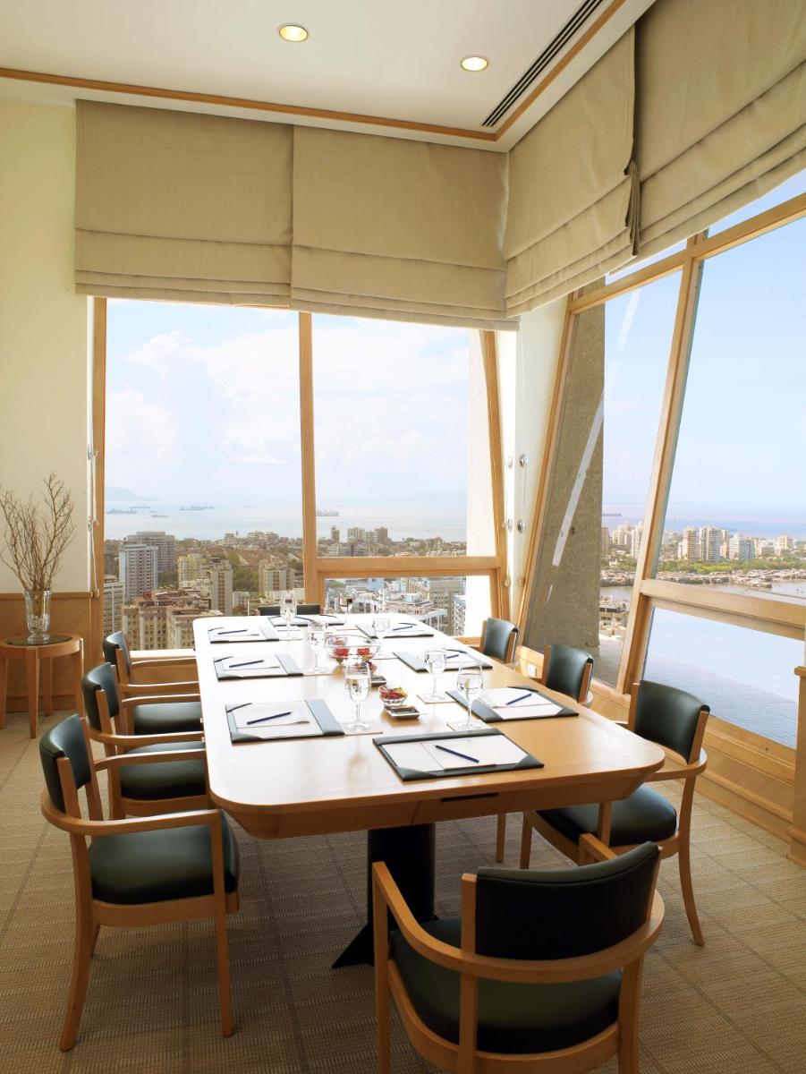 a dining room with a table and chairs and large windows at Trident Nariman Point in Mumbai a dining room with a table and chairs and large windows at Trident Nariman Point in Mumbai