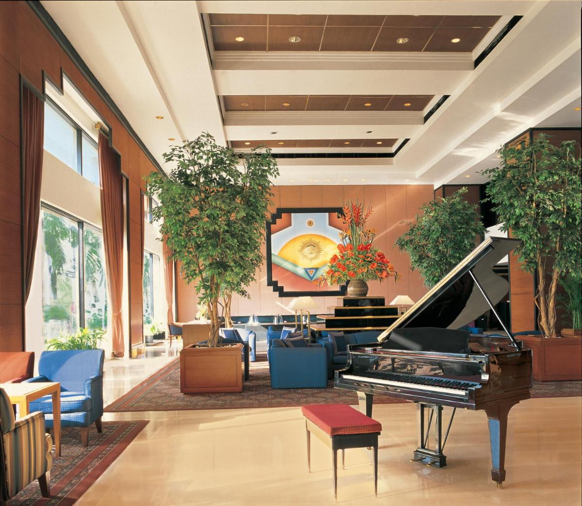 a lobby with a piano and a room with chairs at Trident Nariman Point in Mumbai a lobby with a piano and a room with chairs at Trident Nariman Point in Mumbai