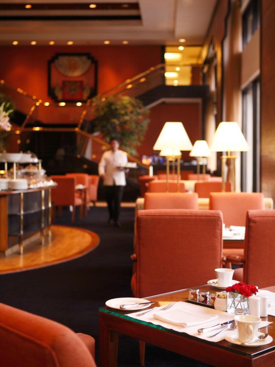 a man walking through a restaurant with tables and chairs at Trident Nariman Point in Mumbai a man walking through a restaurant with tables and chairs at Trident Nariman Point in Mumbai
