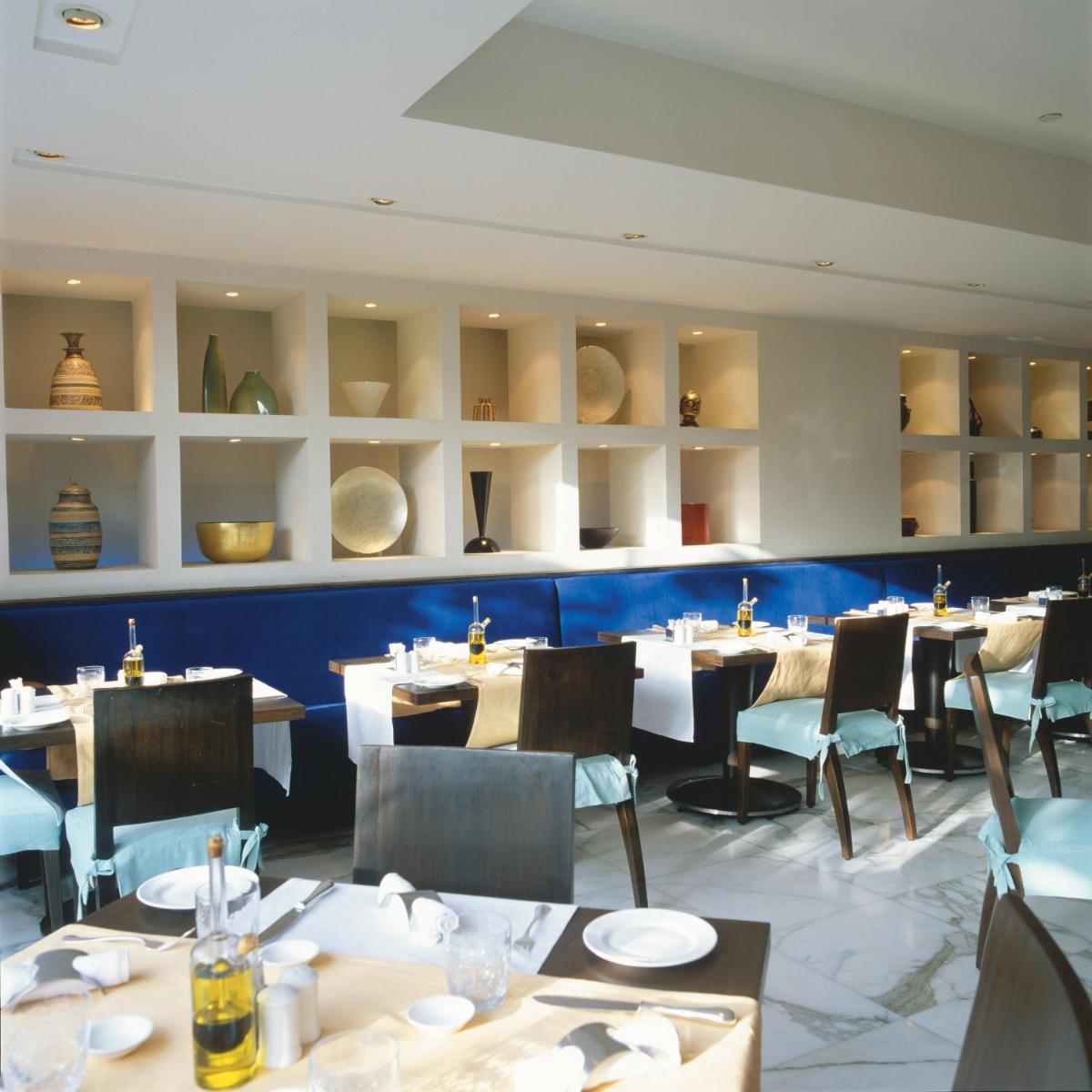 a dining room with tables and chairs and shelves at Trident Nariman Point in Mumbai a dining room with tables and chairs and shelves at Trident Nariman Point in Mumbai