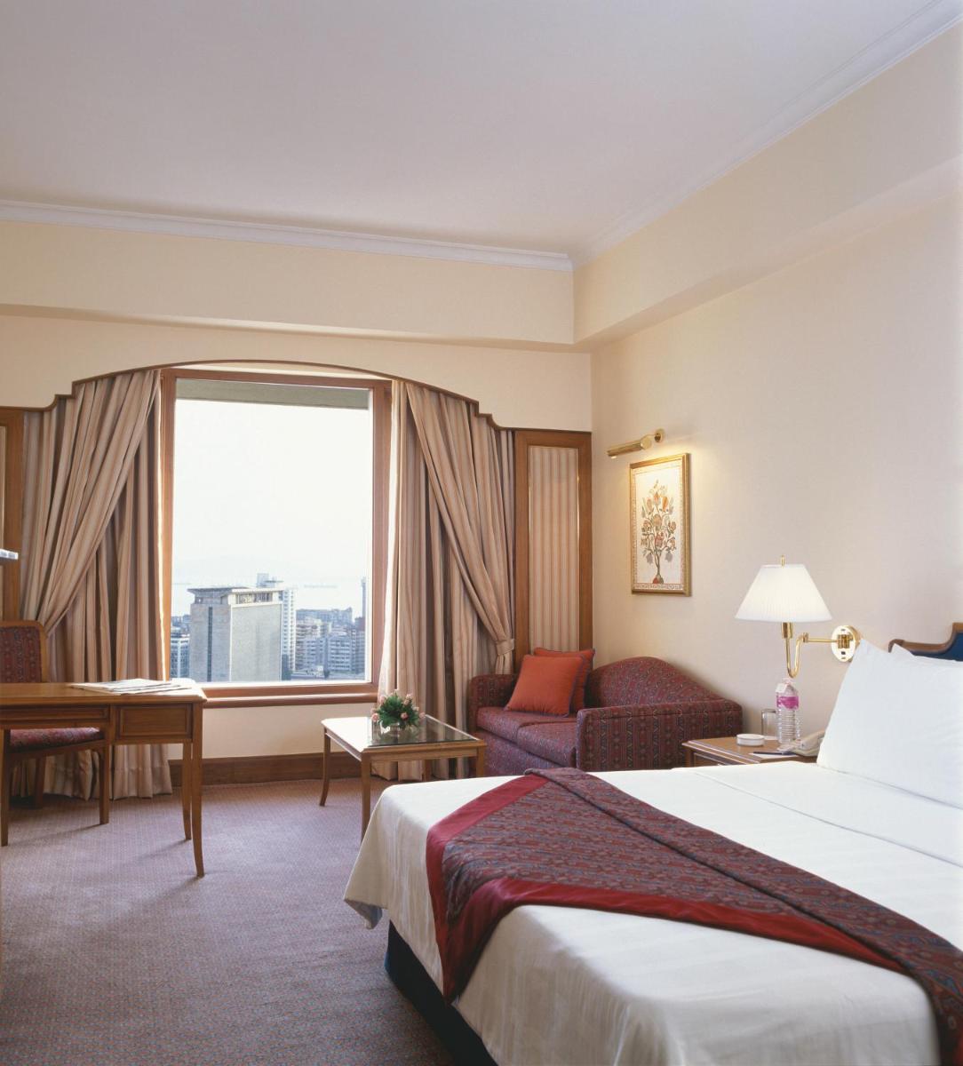 a hotel room with a bed and a large window at Trident Nariman Point in Mumbai a hotel room with a bed and a large window at Trident Nariman Point in Mumbai