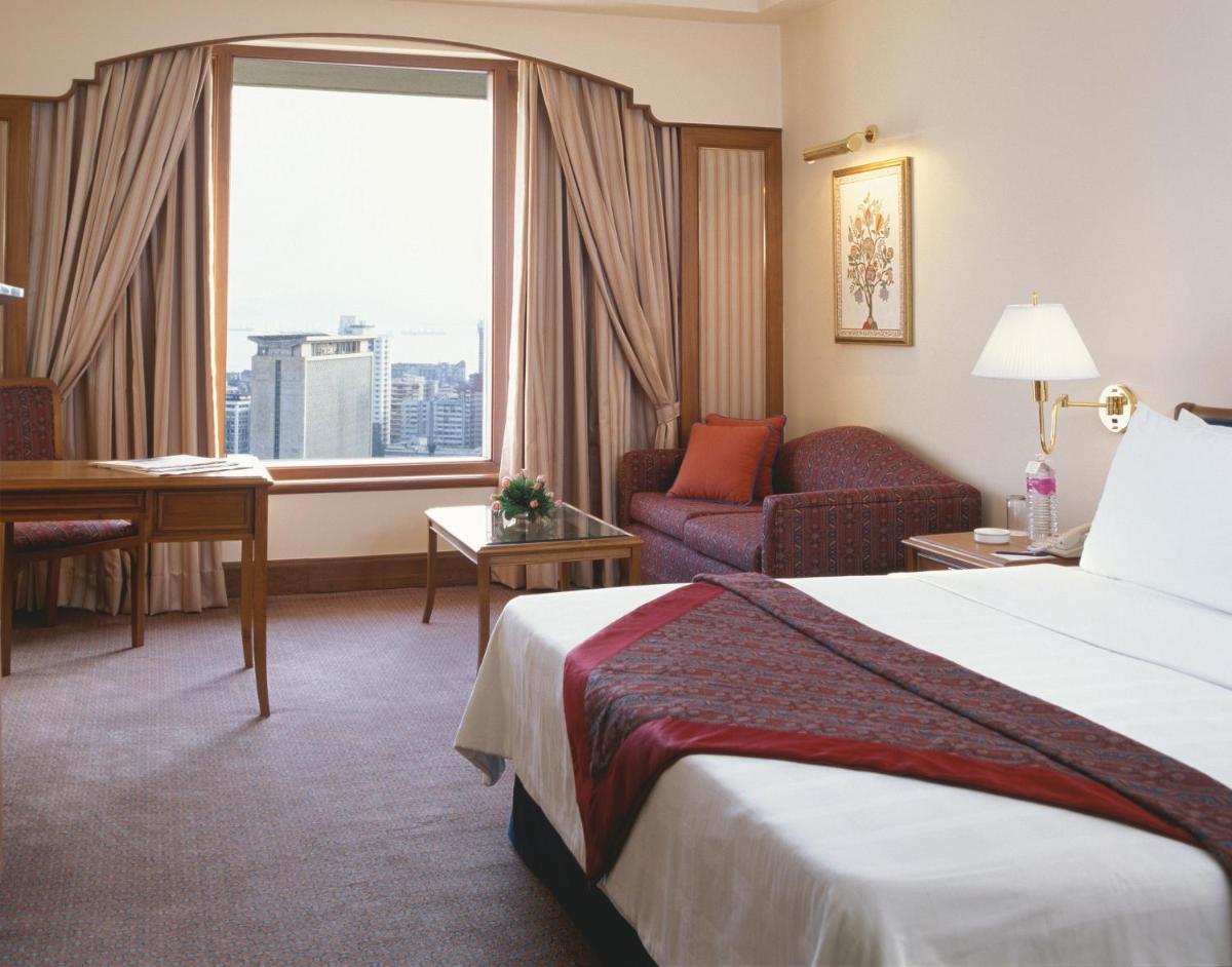 a hotel room with a bed and a desk and a window at Trident Nariman Point in Mumbai a hotel room with a bed and a desk and a window at Trident Nariman Point in Mumbai