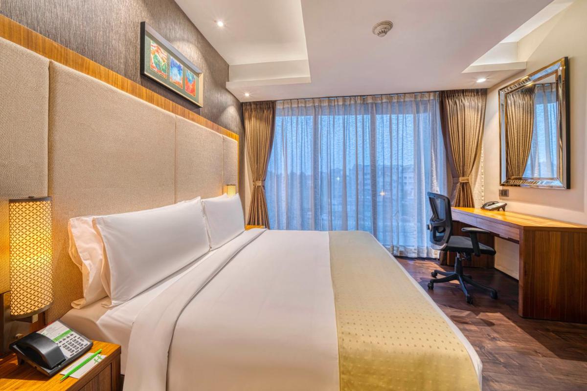 a hotel room with a large bed and a desk at Holiday Inn Kolkata Airport by IHG in Kolkata