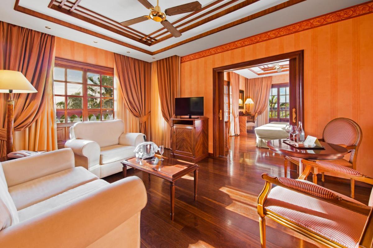 Una sala de estar con muebles blancos y un televisor. en Elba Palace Golf Boutique Hotel - Adults Only, en Caleta de Fuste