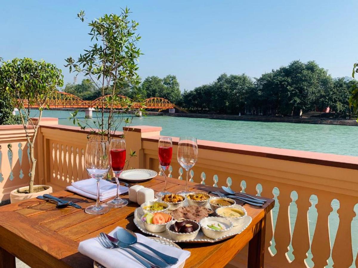 a table with a plate of food and wine glasses at Pilibhit House, Haridwar – IHCL SeleQtions in Haridwār