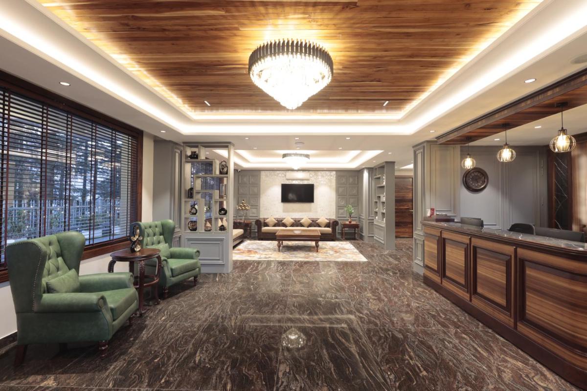 a lobby with a waiting room with a couch and a tv at WelcomHeritage Elysium Resort & Spa in Shimla