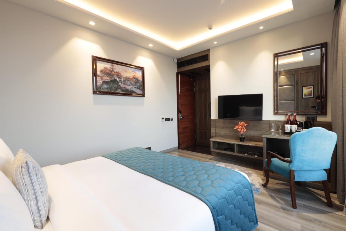 a bedroom with a bed and a desk and a chair at WelcomHeritage Elysium Resort & Spa in Shimla