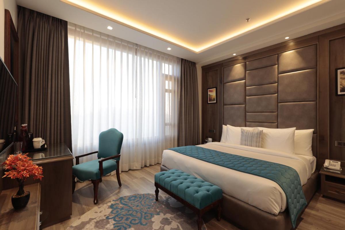 a hotel room with a bed and a desk and chair at WelcomHeritage Elysium Resort & Spa in Shimla