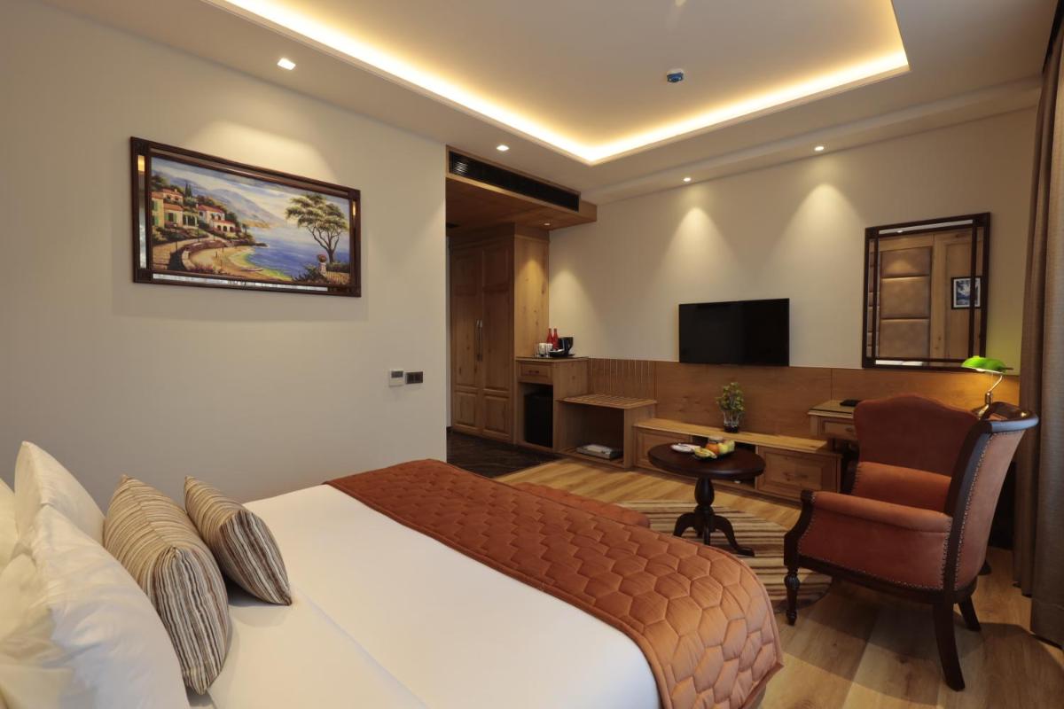 a hotel room with a bed and a desk and a chair at WelcomHeritage Elysium Resort & Spa in Shimla