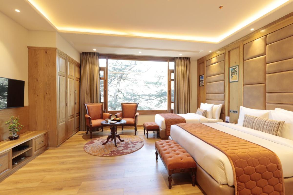a hotel room with a large bed and a window at WelcomHeritage Elysium Resort & Spa in Shimla