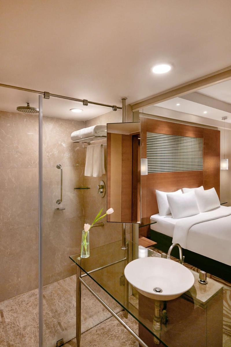 a bedroom with a bed and a bathroom with a shower at Radisson Blu Hotel Ahmedabad in Ahmedabad