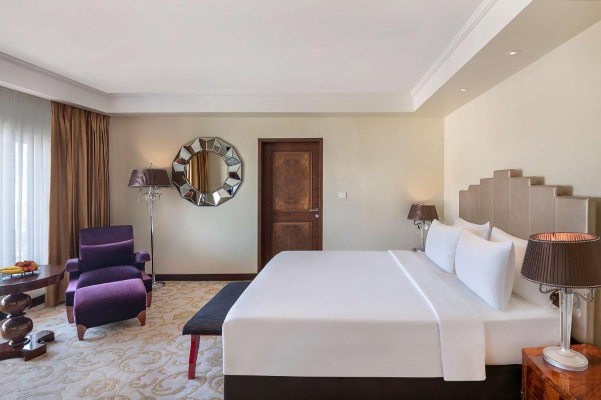 a bedroom with a large white bed and a purple chair at Radisson Blu Hotel Ahmedabad in Ahmedabad