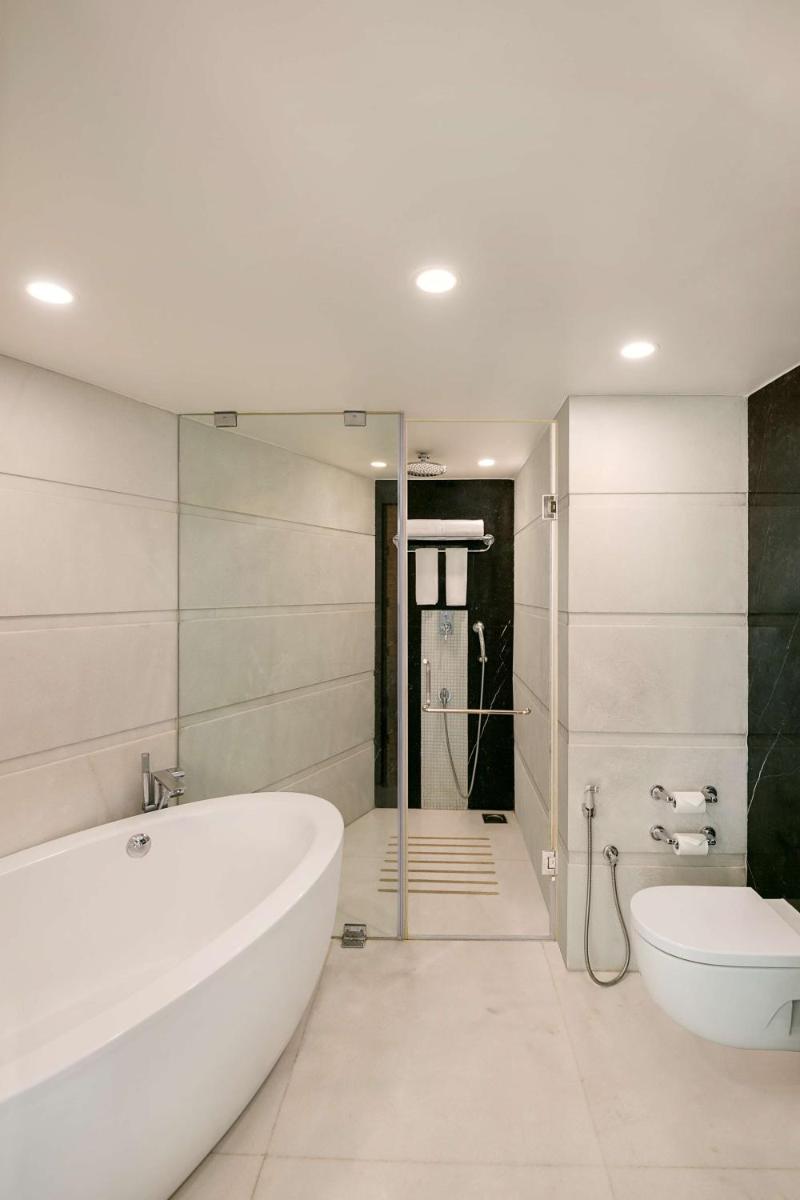 a white bathroom with a tub and a toilet at Radisson Blu Hotel Ahmedabad in Ahmedabad