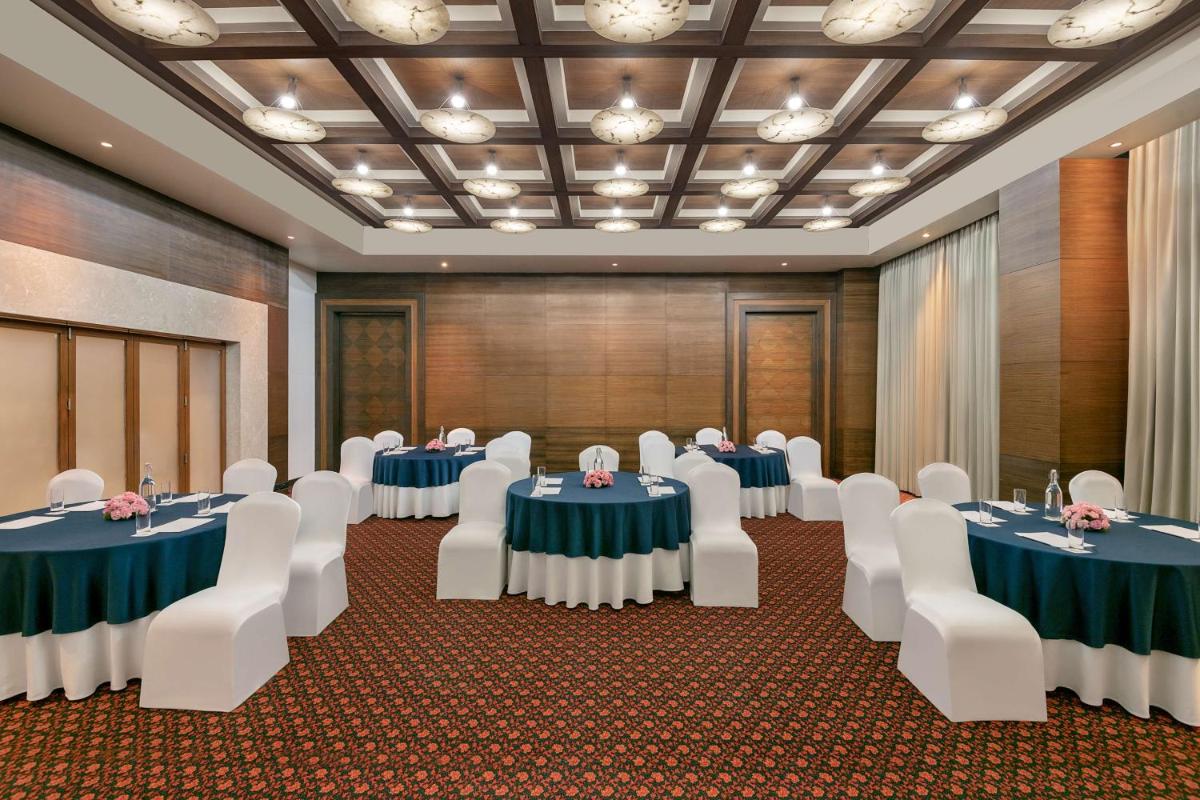 a conference room with tables and chairs in a room at Radisson Blu Hotel Ahmedabad in Ahmedabad
