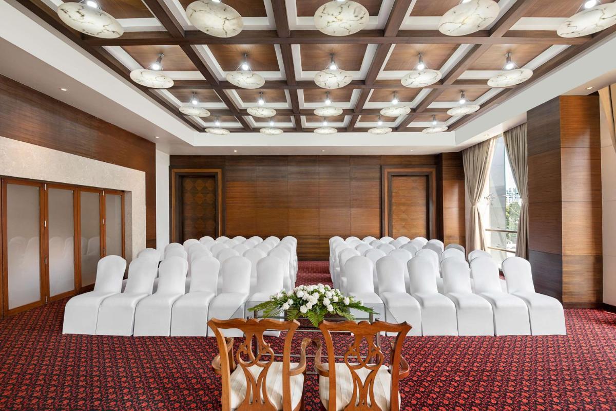 a room with white chairs and a table with flowers at Radisson Blu Hotel Ahmedabad in Ahmedabad