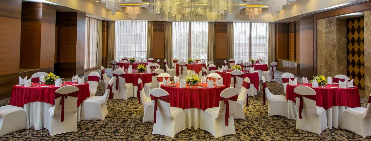 a banquet hall with red and white tables and chairs at Radisson Blu Hotel Ahmedabad in Ahmedabad