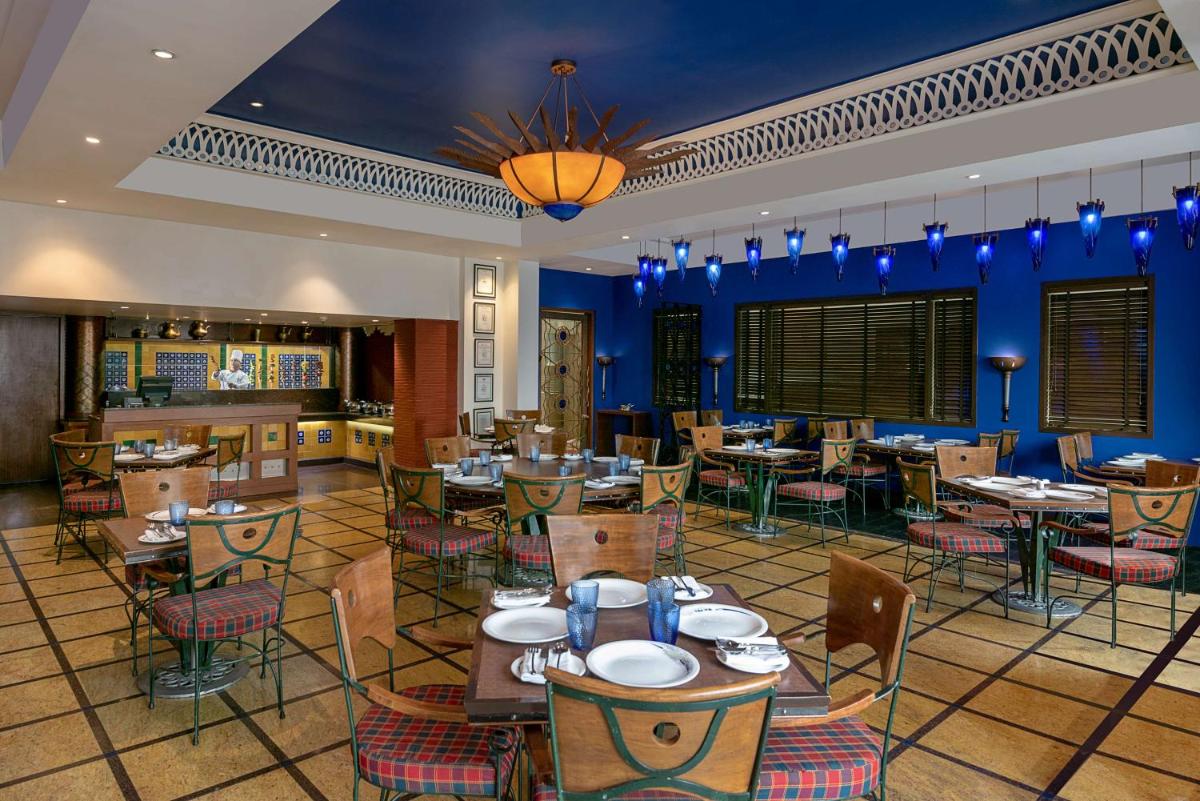 a dining room with tables and chairs and blue walls at Radisson Blu Hotel Ahmedabad in Ahmedabad