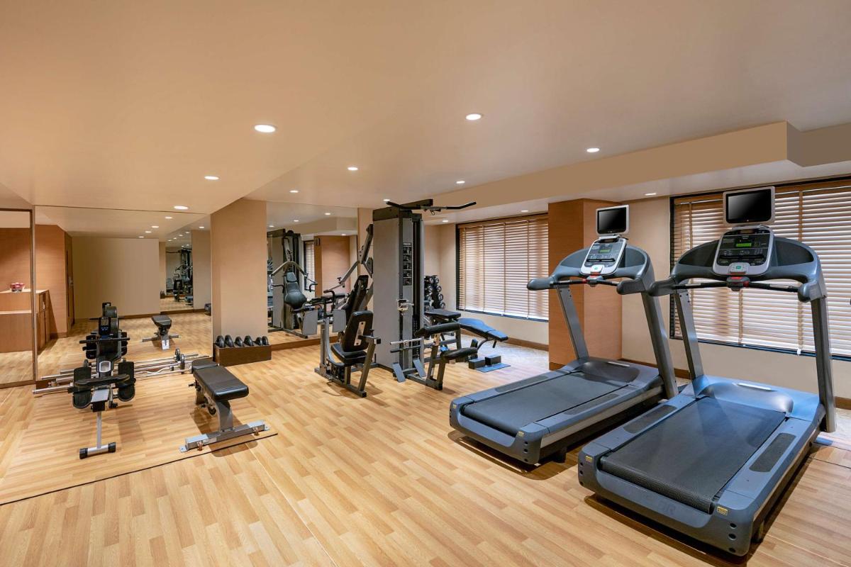 a gym with several treadmills and elliptical machines at Radisson Blu Hotel Ahmedabad in Ahmedabad