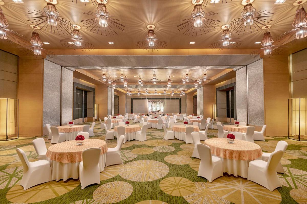 a banquet hall with tables and chairs and chandeliers at Radisson Blu Hotel Amritsar in Amritsar