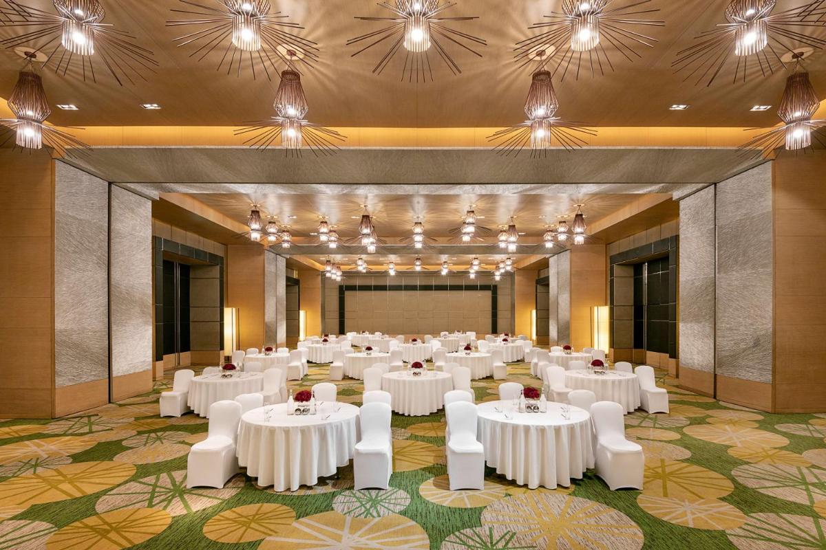 a banquet hall with white tables and white chairs at Radisson Blu Hotel Amritsar in Amritsar